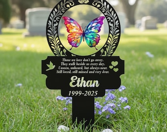 Può includere: Paletto commemorativo in metallo nero con un design a farfalla colorata. La farfalla è inserita in una cornice circolare con dettagli floreali. Il paletto include il nome "Ethan" e le date 1999-2025, insieme a una citazione.