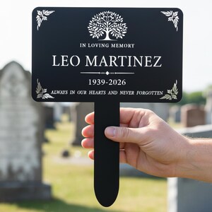 Puede incluir: Marcador conmemorativo negro con texto blanco. El marcador dice "IN LOVING MEMORY LEO MARTINEZ 1939-2026 ALWAYS IN OUR HEARTS AND NEVER FORGOTTEN." Un gr&aacute;fico de &aacute;rbol est&aacute; en la parte superior. Elementos florales decorativos en cada esquina.