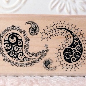 Puede incluir: Dos bloques de madera con diseños de paisley. Un bloque tiene un diseño de paisley rojo y el otro bloque tiene un diseño de paisley negro.