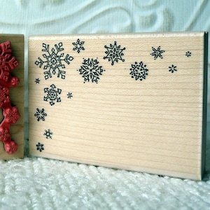 May include: Two wooden blocks with snowflake designs. The block on the left has red snowflakes arranged in a corner design. The block on the right has black snowflakes scattered across the surface.
