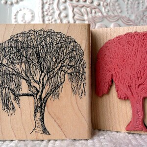 May include: Two wooden blocks featuring different tree designs. The first block displays a black and white line drawing of a weeping willow tree. The second block features a red rubber stamp of a tree with a thick trunk and branches.