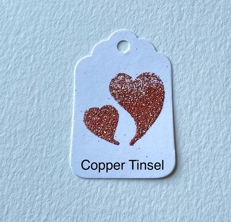 May include: A white gift tag with two copper glitter hearts and the text "Copper Tinsel".