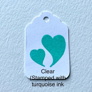 May include: A white tag with two turquoise hearts stamped on it. The tag says "Clear (Stamped with turquoise ink".