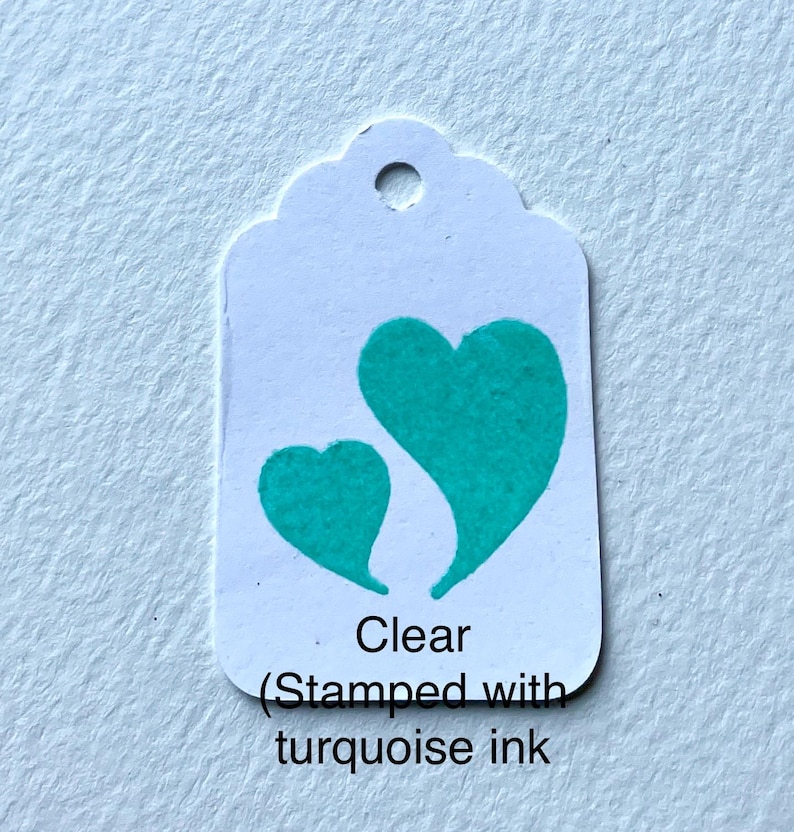 May include: A white tag with two turquoise hearts stamped on it. The tag says "Clear (Stamped with turquoise ink".