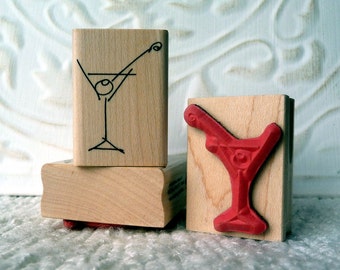 May include: Two wooden stamps featuring a martini glass design. One stamp is black and white and the other is red.