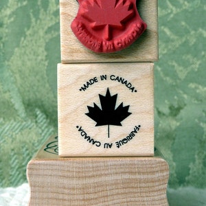 May include: Three wooden stamps with a Canadian maple leaf design. The top stamp reads "Proudly Made in Canada". The middle stamp reads "Made in Canada. Fabriqué au Canada". The bottom stamp is blank.