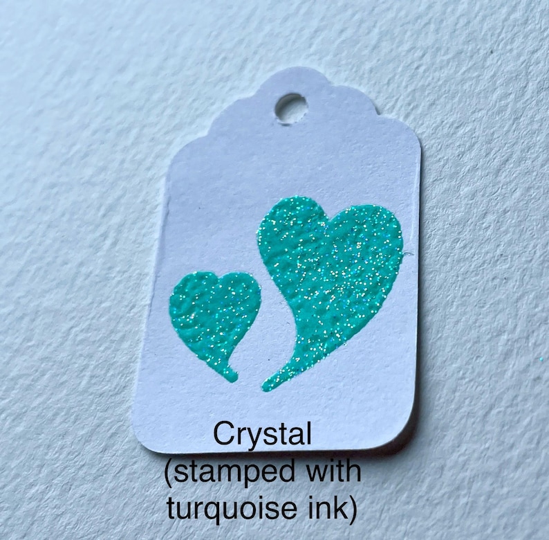 May include: White tag with a turquoise heart design. The tag reads "Crystal (stamped with turquoise ink)"
