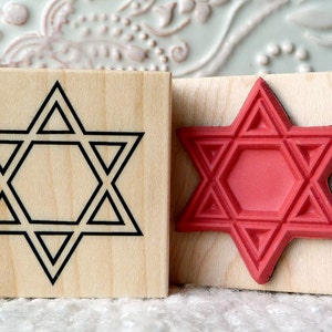 May include: Two wooden stamps with a Star of David design. One stamp has a black outline and the other has a red, raised design.
