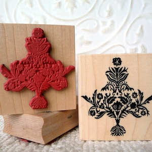 Può includere: Due timbri in gomma montati su legno con disegni floreali. Il timbro a sinistra ha un disegno floreale rosso e il timbro a destra ha un disegno floreale nero.
