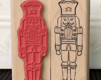 May include: Two wooden stamps of a nutcracker. One stamp is red and the other is black and white.