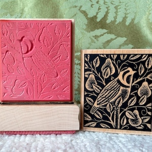 Può includere: Due timbri in gomma montati su legno con un design di uccello e pera. Il timbro a sinistra è rosso e il timbro a destra è nero.