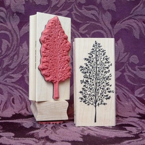 May include: Two wooden rubber stamps with tree designs. The first stamp features a red tree with a detailed design. The second stamp features a black tree with a simple design. Both stamps are labelled "Cole's Inkwell" on the side.