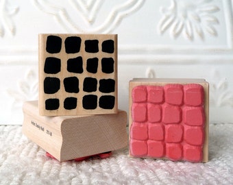 Könnte beinhalten: Drei Holzstempel mit verschiedenen Mustern. Der obere Stempel hat ein schwarz-weißes geometrisches Muster. Der mittlere Stempel ist leer. Der untere Stempel hat ein rotes Ziegelmuster. Der untere Stempel ist mit "Annie Emily Hall 501B" beschriftet.