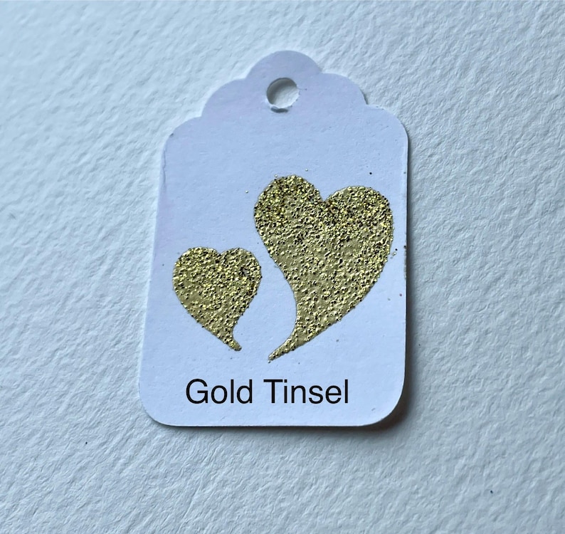 May include: White gift tag with two gold glitter hearts and the text "Gold Tinsel".
