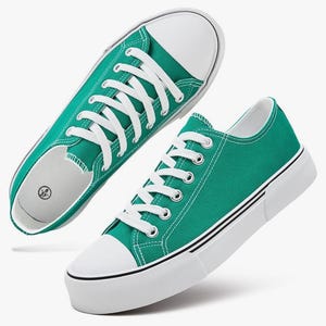 May include: A pair of teal canvas sneakers featuring white laces, white rubber toe caps, and thick white soles with a thin black stripe detail. The interior of the shoe shows a size label with the numbers 6 and 37 printed in a black circular icon.