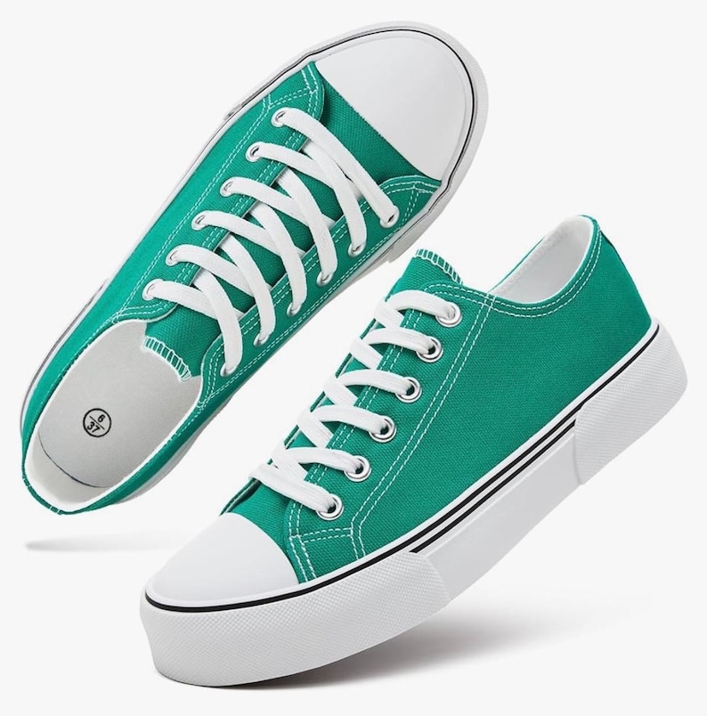 May include: A pair of teal canvas sneakers featuring white laces, white rubber toe caps, and thick white soles with a thin black stripe detail. The interior of the shoe shows a size label with the numbers 6 and 37 printed in a black circular icon.