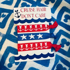 Op de afbeelding: Een kaart met de tekst "CRUISE HAIR DON'T CARE" en verschillende haarbanden. De haarbanden zijn rood en blauw met witte anker- en sterpatronen. De kaart heeft een blauw golfpatroon.