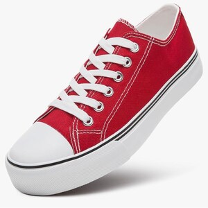 May include: A low-top sneaker featuring a vibrant red canvas upper, white laces, and a white rubber toe cap. The shoe includes a thick white platform sole with a thin black stripe detail running along the side, providing a classic athletic look.