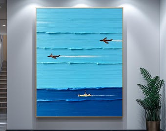 Op de afbeelding: Een abstract olieverfschilderij met blauwe en witte tinten. Het kunstwerk toont een zeegezicht met drie vliegtuigen en een boot. Het schilderij is ingelijst in een goudkleurige lijst en hangt aan een witte muur.