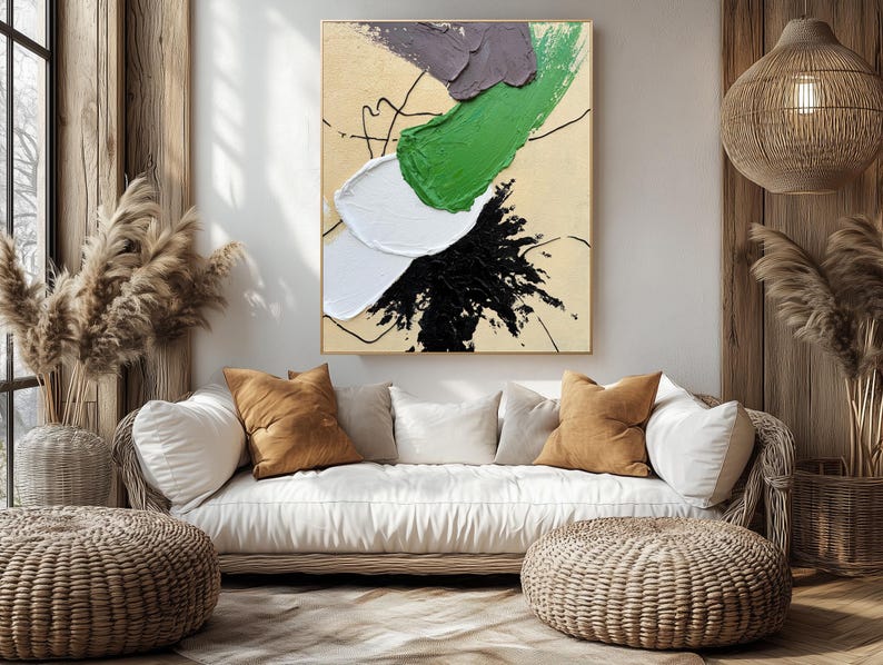 Pode incluir: Um sof&aacute; branco com almofadas marrons fica em frente a uma grande pintura abstrata com tinta verde, preta, branca e roxa. A pintura est&aacute; em uma parede bege. O sof&aacute; est&aacute; em uma sala com piso de madeira e uma l&acirc;mpada de vime pendurada no teto.