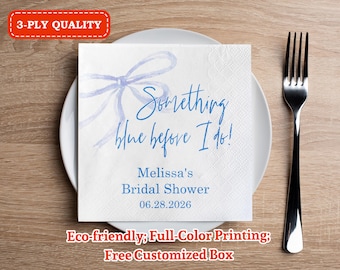 May include: A white square napkin with the text "Something blue before I do!" in blue script, with a blue bow illustration. The napkin is on a white plate, next to a silver fork. The text "Melissa's Bridal Shower 06.28.2026" is also printed on the napkin.