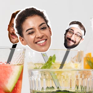 Puede incluir: Vasos de cócteles coloridos, adornados con frutas y menta, con palitos para remover con forma de caras. Una bebida tiene sandía, otra menta y una tercera rodajas de naranja. Fondo claro.