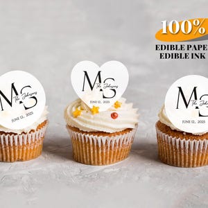 Puede incluir: Tres cupcakes con glaseado blanco, cada uno coronado con un disco de papel comestible blanco. Los discos presentan las iniciales "M S", el nombre "The Johnsons" y la fecha "12 de junio de 2025". También aparece el texto "100% PAPEL COMESTIBLE TINTA COMESTIBLE".