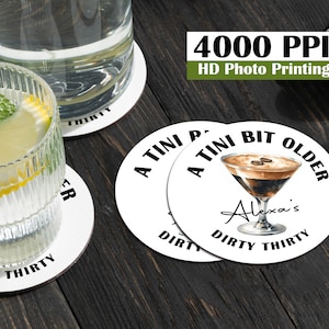 以下が含まれることがあります： 黒い文字とカクテルの黒と茶色のイラストが描かれた白い丸いコースターが3つ。コースターの文字は「A TINI BIT OLDER」、「Alexa's DIRTY THIRTY」、「DIRTY THIRTY」です。