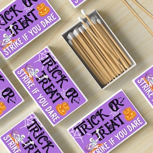 May include: A collection of Halloween-themed matchboxes with the text "Trick or Treat, Strike if you Dare" in black and white on a purple background. A box of matches with white tips is also visible.