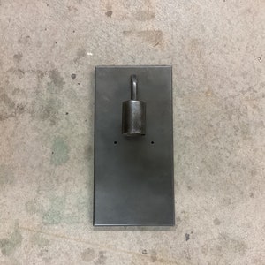 May include: A black metal wall sconce with a single light fixture. The sconce has a rectangular base and a round light fixture with a hook.