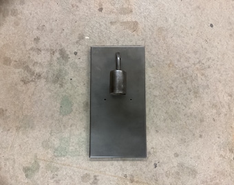 May include: A black metal wall sconce with a single light fixture. The sconce has a rectangular base and a round light fixture with a hook.