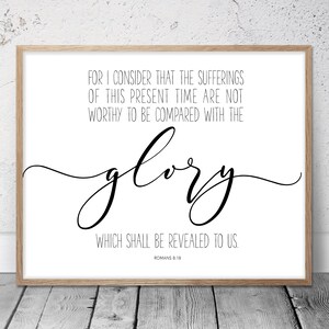 May include: A framed print with a light wood frame. The print features the words "FOR I CONSIDER THAT THE SUFFERINGS OF THIS PRESENT TIME ARE NOT WORTHY TO BE COMPARED WITH THE glory WHICH SHALL BE REVEALED TO US. ROMANS 8:18" in black script.