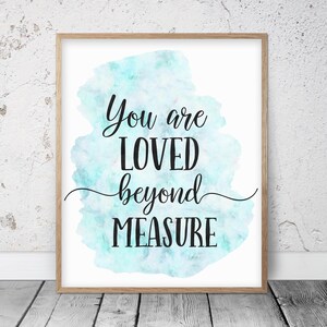Puede incluir: Una impresión enmarcada con un fondo de acuarela en tonos azules y verdes. La impresión presenta el texto "You are loved beyond measure" en fuente cursiva negra.