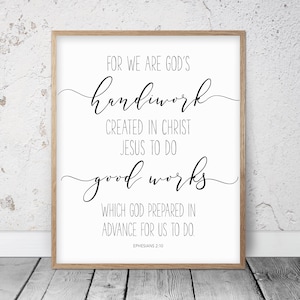 May include: A framed print with the text "FOR WE ARE GOD'S handiwork CREATED IN CHRIST JESUS TO DO good works WHICH GOD PREPARED IN ADVANCE FOR US TO DO. EPHESIANS 2:10" in black script and block lettering. The frame is a light brown color.