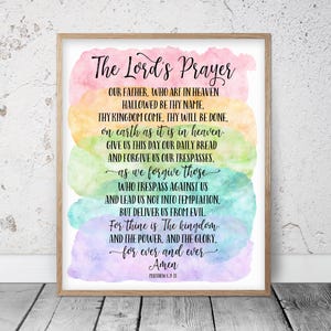 May include: A watercolour print with a rainbow background featuring the Lord's Prayer in black text. The text includes the words "Our Father, who art in heaven, hallowed be thy name." and "For thine is the kingdom, and the power, and the glory, for ever and ever. Amen."