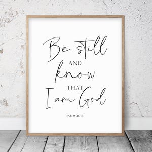 Op de afbeelding: Een zwart-witte printbare wandkunstprint met de tekst "Be still and know that I am God" en de bijbelverwijzing "Psalm 46:10".