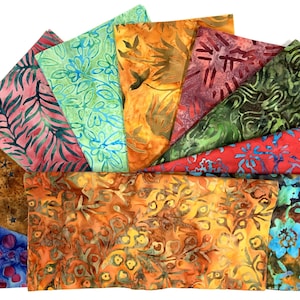 May include: A collection of colorful batik fabric squares arranged in a fan shape. The fabrics feature various patterns, including floral, leaf, and abstract designs, in shades of blue, green, red, orange, and brown. The fabric squares are likely for quilting or crafting.