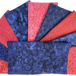 May include: A collection of folded fabric squares in shades of red and blue. The fabrics display various patterns, including floral, swirls, and small dots. The arrangement creates a fan-like display, showcasing the different designs and colors.