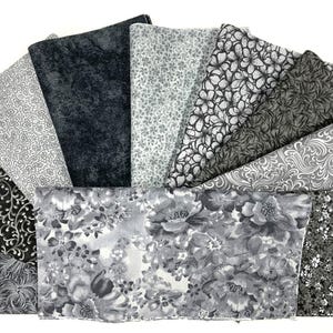 May include: A set of three ceramic mugs with a speckled, matte finish. The mugs are in shades of cream, light gray, and dark gray. Each mug has a simple, minimalist design and a rounded handle.