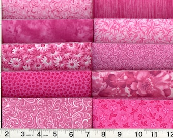 May include: A collection of pink fabric swatches with various patterns, including floral, swirls, and textured designs. The fabrics are arranged side by side, with a ruler along the left edge showing measurements in inches.