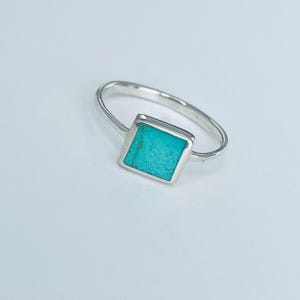May include: A silver ring with a square turquoise stone.