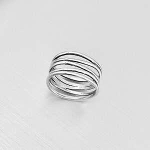 May include: A silver ring with five bands stacked on top of each other. The bands are smooth and have a slightly hammered texture.