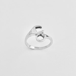 May include: A silver ring shaped like a wrench with a hexagonal nut on the end.