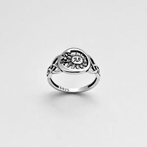 May include: A silver ring with a sun and moon design. The ring is marked with "S925" on the inside band.