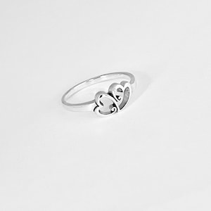 May include: A silver ring with two interlocking heart designs.