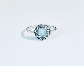 May include: A silver ring with a white opal gemstone set in a delicate floral design.