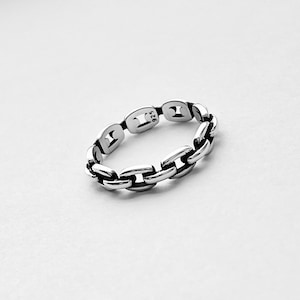 May include: A silver chain link ring. The ring is made of a series of interlocking links, creating a textured and modern look.