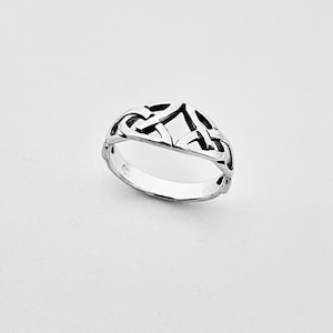 May include: A polished silver ring featuring an openwork design with interconnected loops and geometric shapes. The band has a smooth, rounded interior surface and a detailed, textured top section that forms a continuous, repeating pattern.