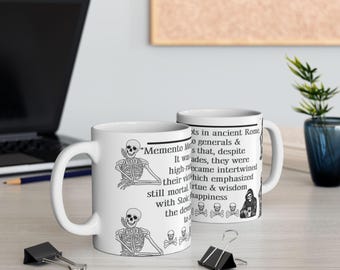 May include: White ceramic coffee mug with a black and white illustration of a skeleton sitting with the text "Memento Mori" and a quote about ancient Roman generals.