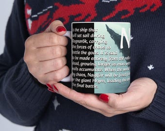 Puede incluir: Una taza de cerámica negra y azul con un asa blanca. La taza presenta una ilustración en blanco y negro de un barco con el texto "N es la nave que zarpará durante el Ragnarök, llevando las fuerzas del caos para luchar contra los dioses. Se dice que está hecha completamente de los clavos de los muertos, que crecen a medida que se acumulan más clavos. Cuando el mundo es consumido por el caos, Naglfar será liberado para el gigante Hrym, liderando el ejército hacia la batalla final."